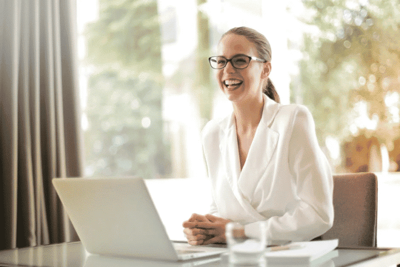 A woman smiling using a laptop for a company training game.